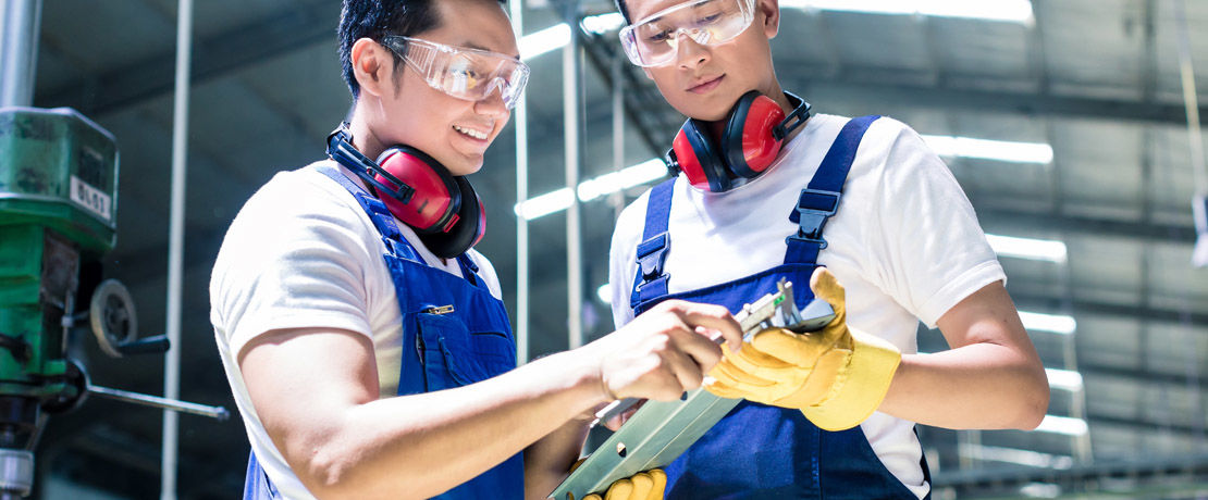 two production workers checking their clipboard