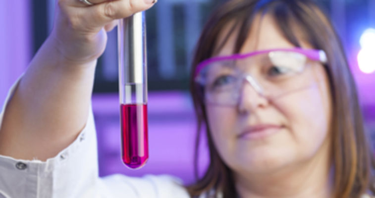 scientist looking at vial of liquid