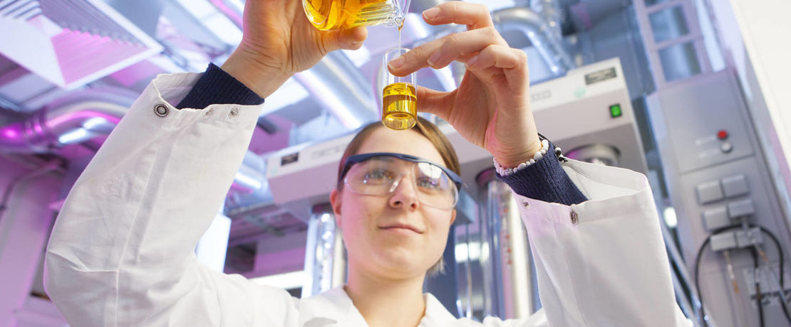 woman in the lab holding a test tube filled with oil